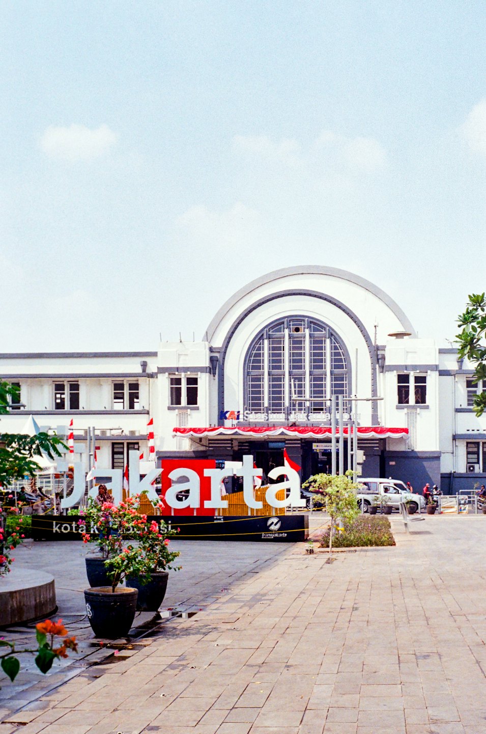 White Jakarta sign sitting in front of a historic train station.
