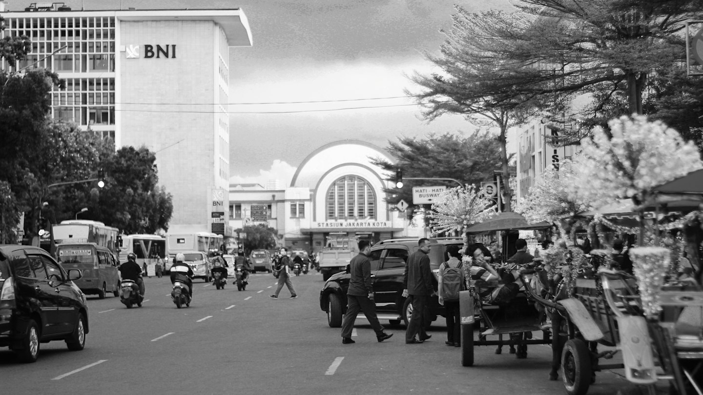 Pedestrians and vehicles pass the historic Stasiun Jakarta Kota station.